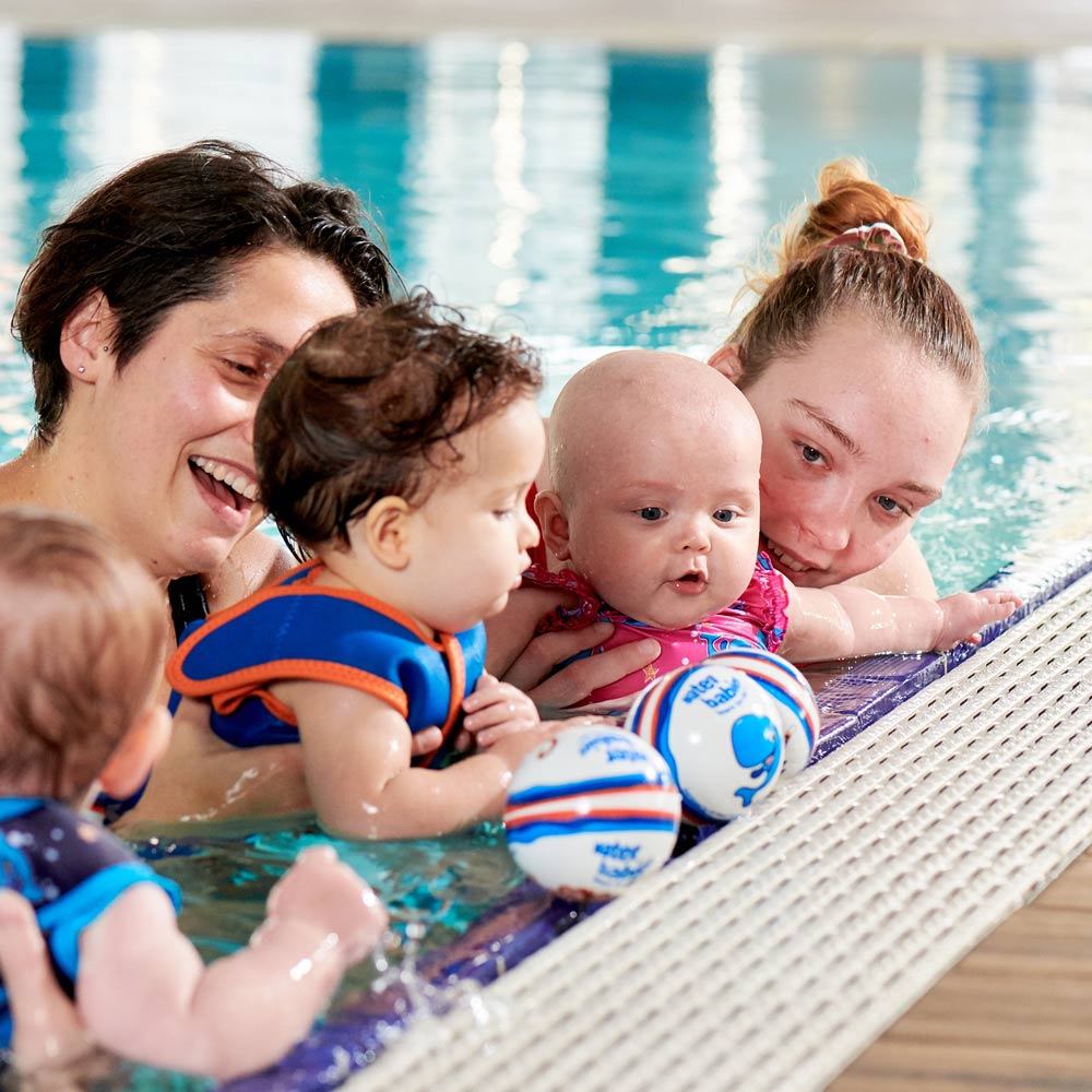 mums and babies in water babies lesson at poolside with swim balls